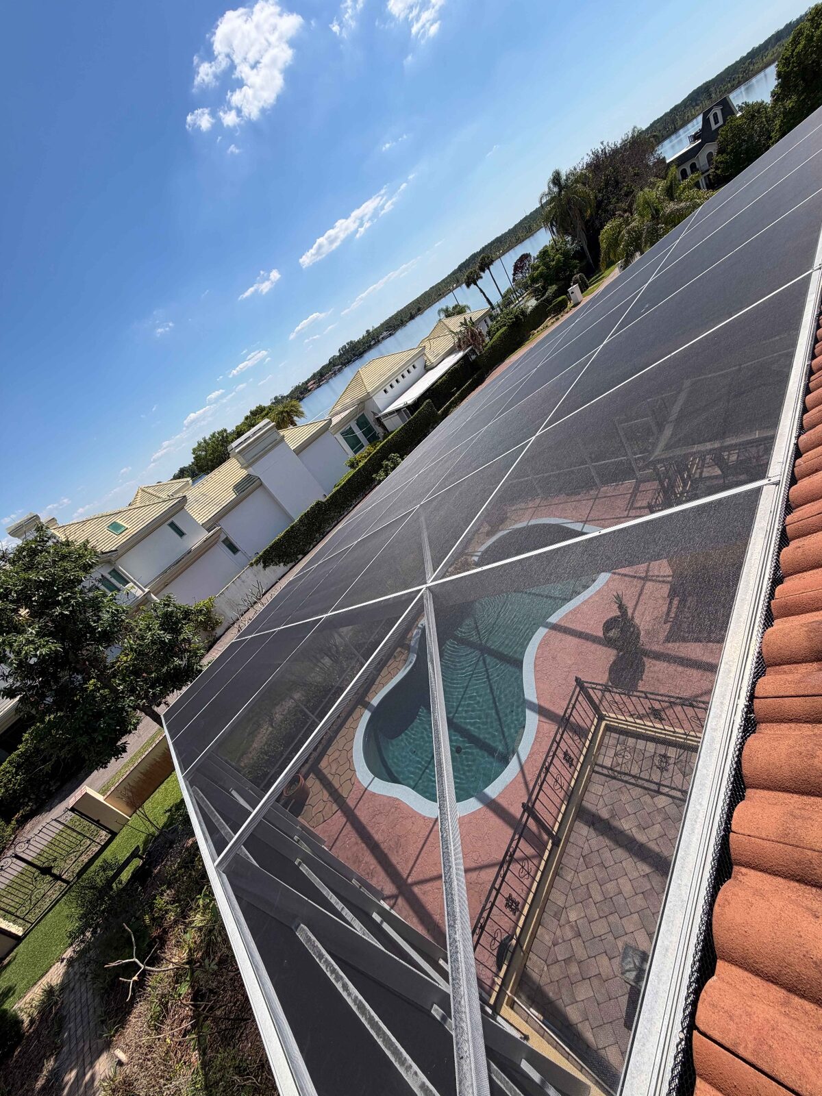 Screen enclosure panels viewed from the roofline above a lakefront pool deck