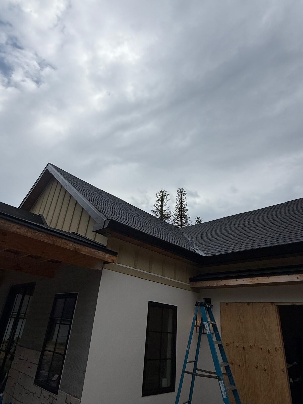 Black gutters and fascia installed along the rooflines and gable of a home under construction