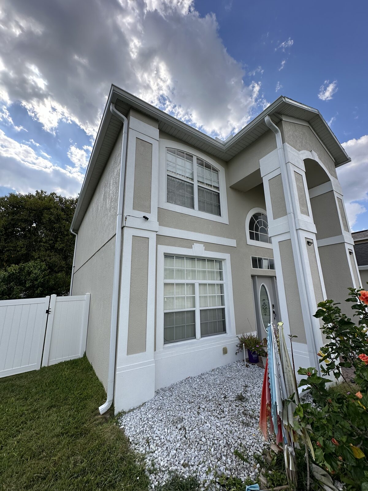 White gutters, fascia and a full-height downspout along the side elevation of a two-story stucco home