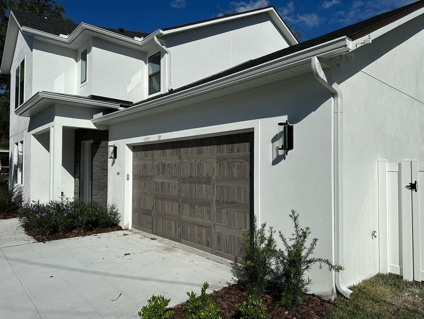 White seamless gutter run, fascia and downspout installed along the roofline of a white stucco home