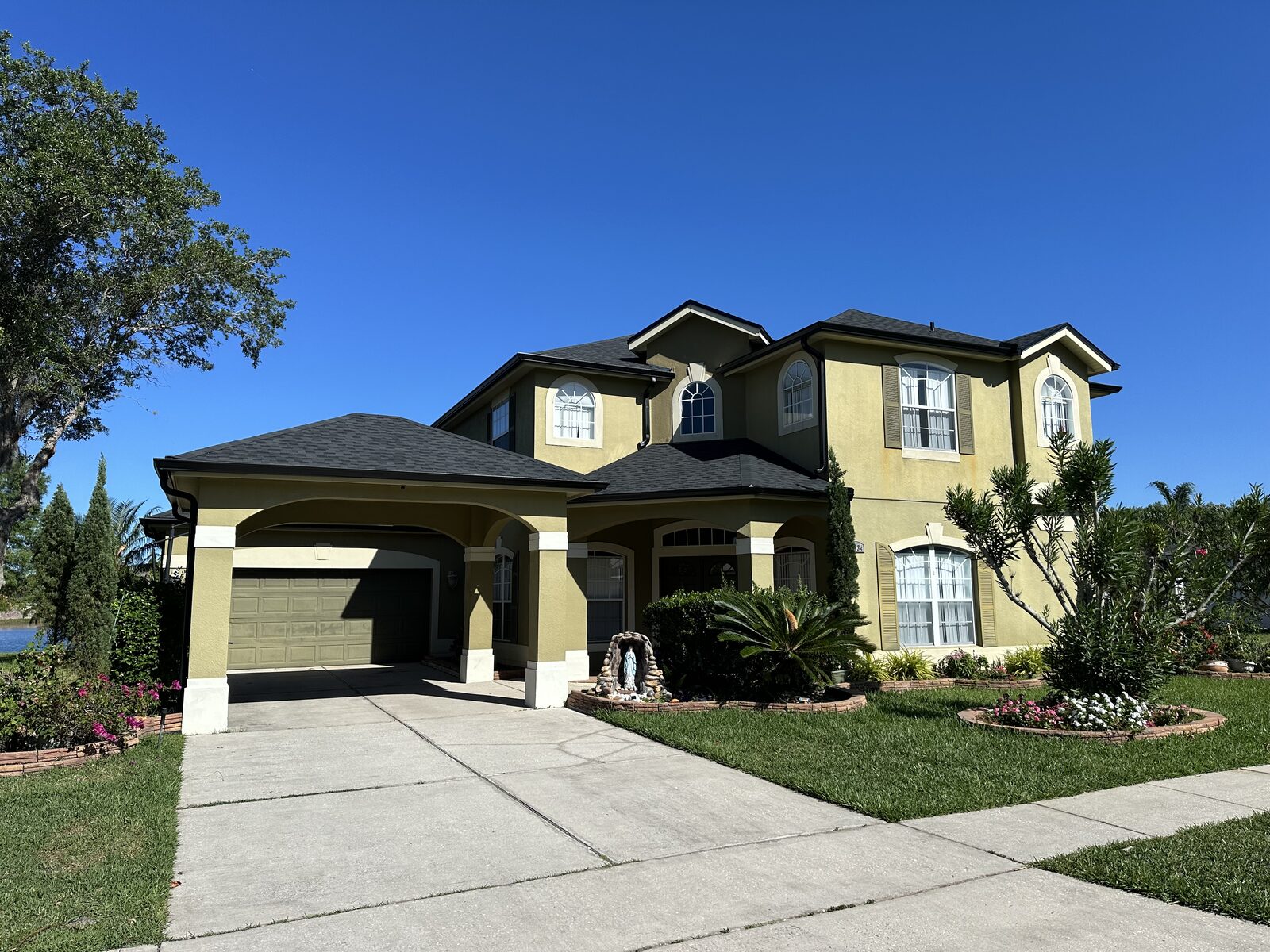 Two-story stucco home with dark roofline, gutters and downspouts along the front elevation
