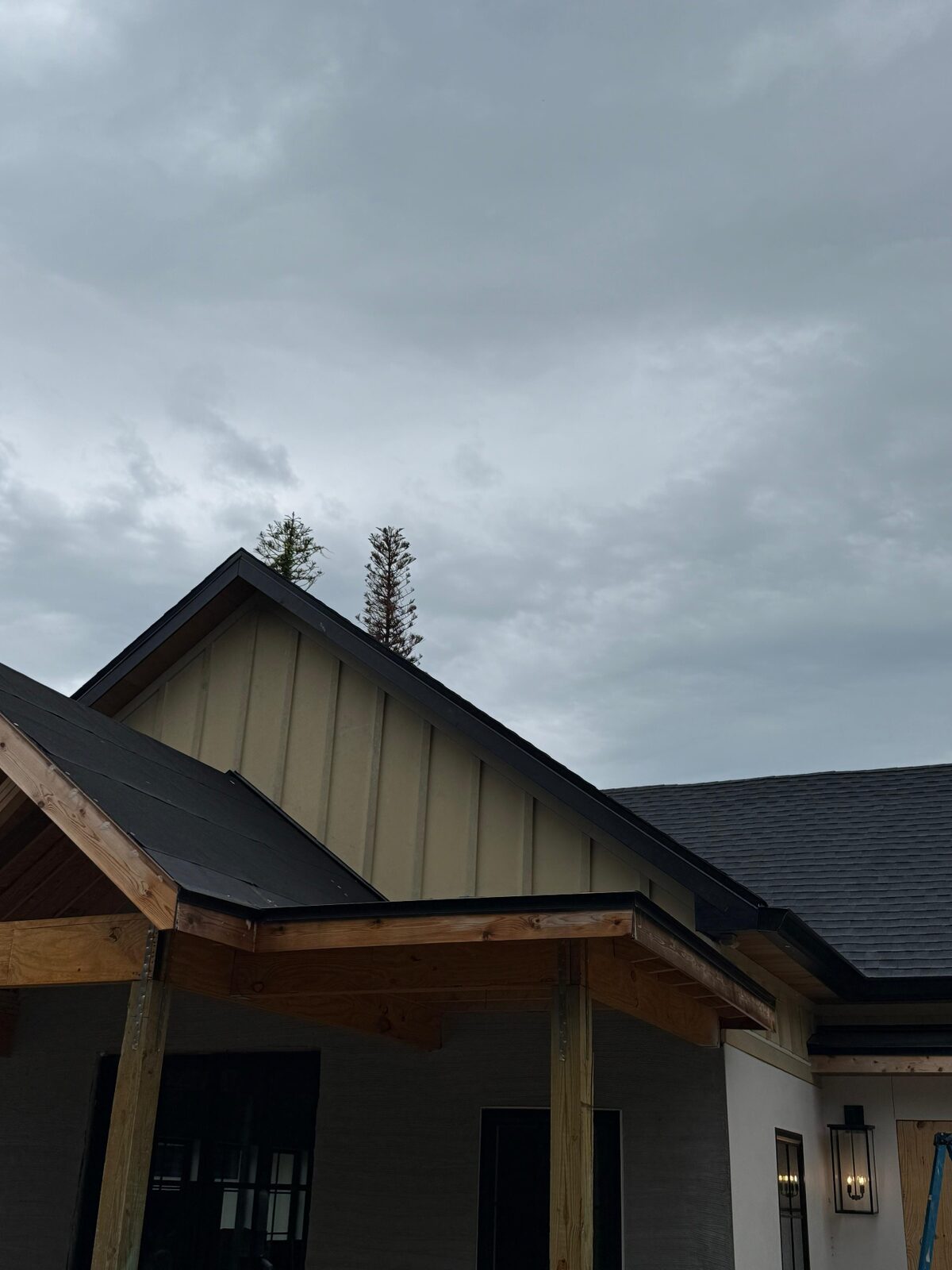 Vertical board-and-batten gable siding finished with black fascia and gutter trim over a covered porch