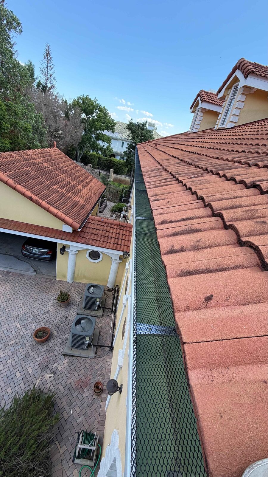 Leaf guard screen installed over a white gutter along a barrel tile roofline