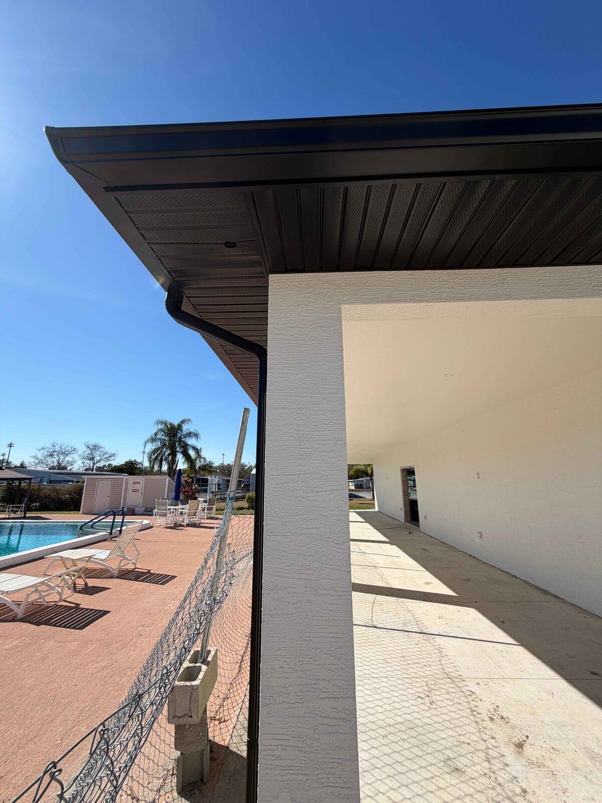 Dark bronze soffit and fascia finished under the eave of a white stucco home
