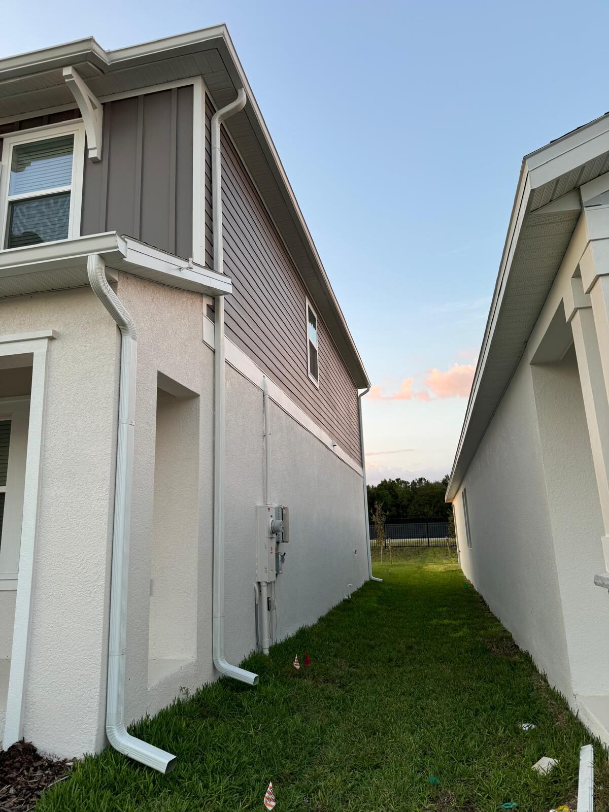 White board-and-batten siding with dark seamless gutters on a two-story home