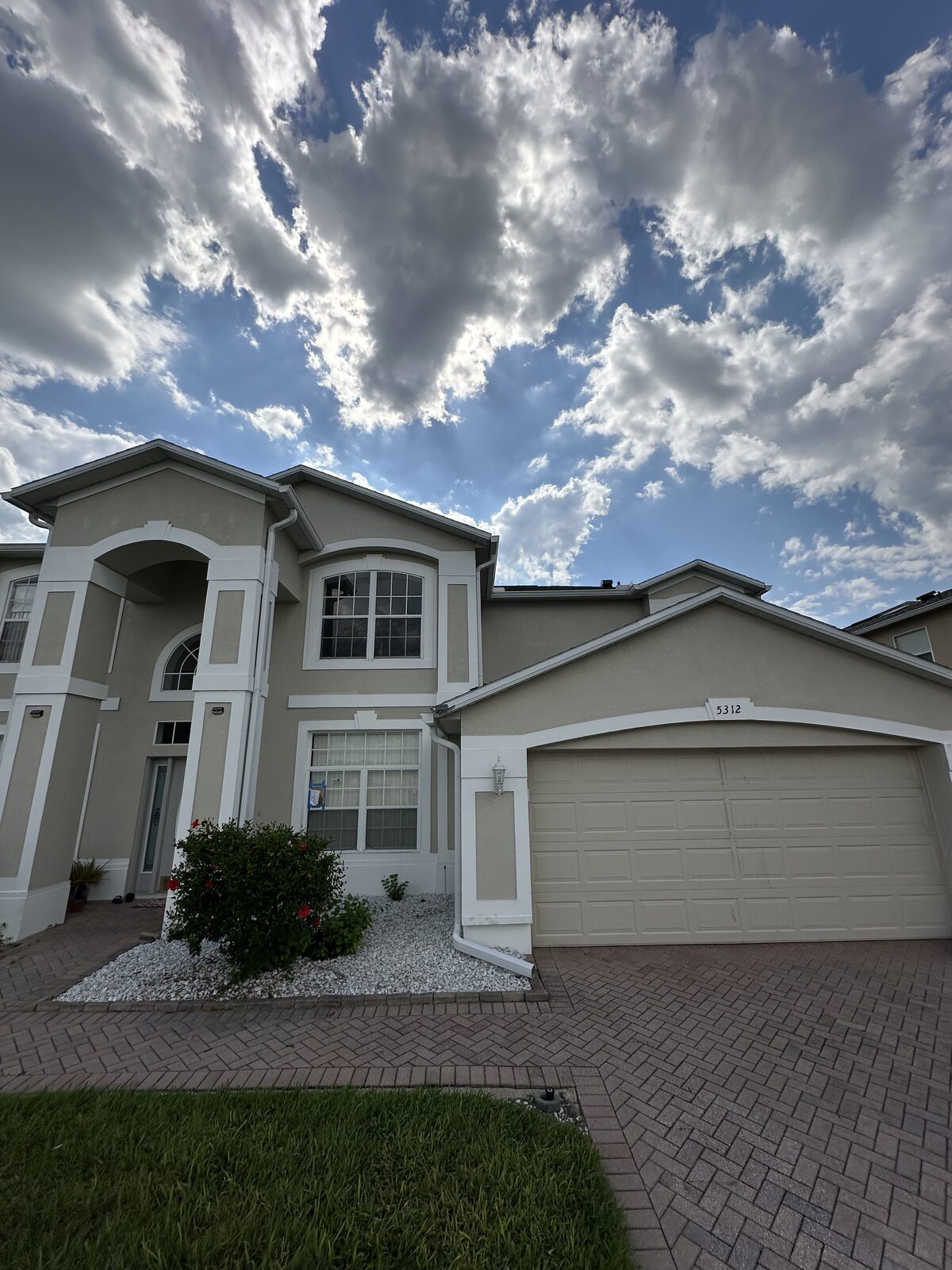 White gutters and downspouts along the entry and garage rooflines of a two-story stucco home